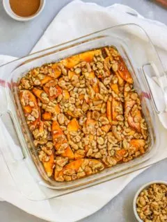 a container of apple strudel cake with a bowl of cinnamon and walnuts on the side