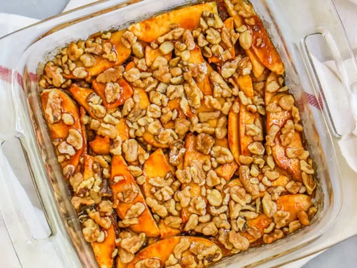 a container of apple strudel cake with a bowl of cinnamon and walnuts on the side