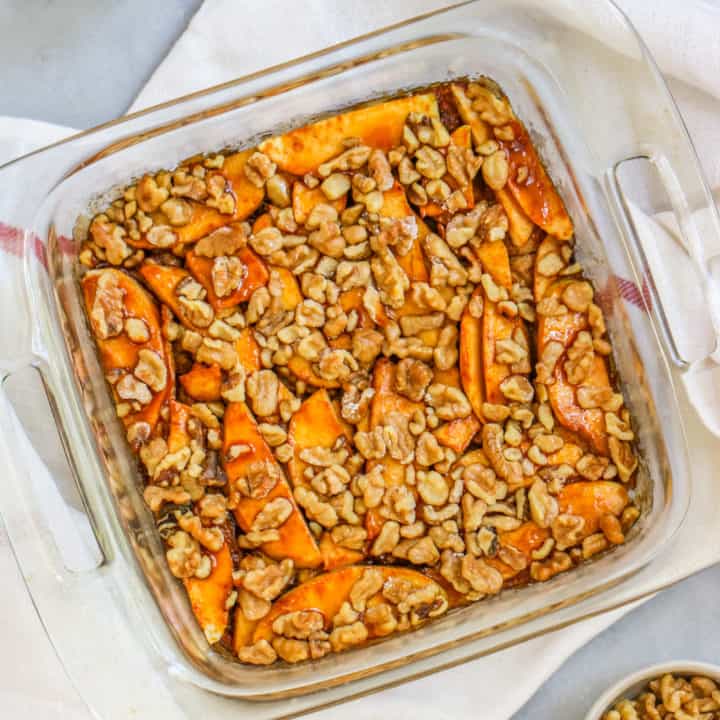 a container of apple strudel cake with a bowl of cinnamon and walnuts on the side