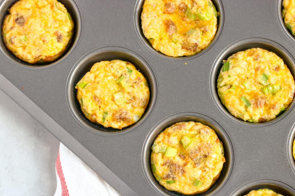 a horizontal image with a corner shot of the sausage egg muffins in the tin 