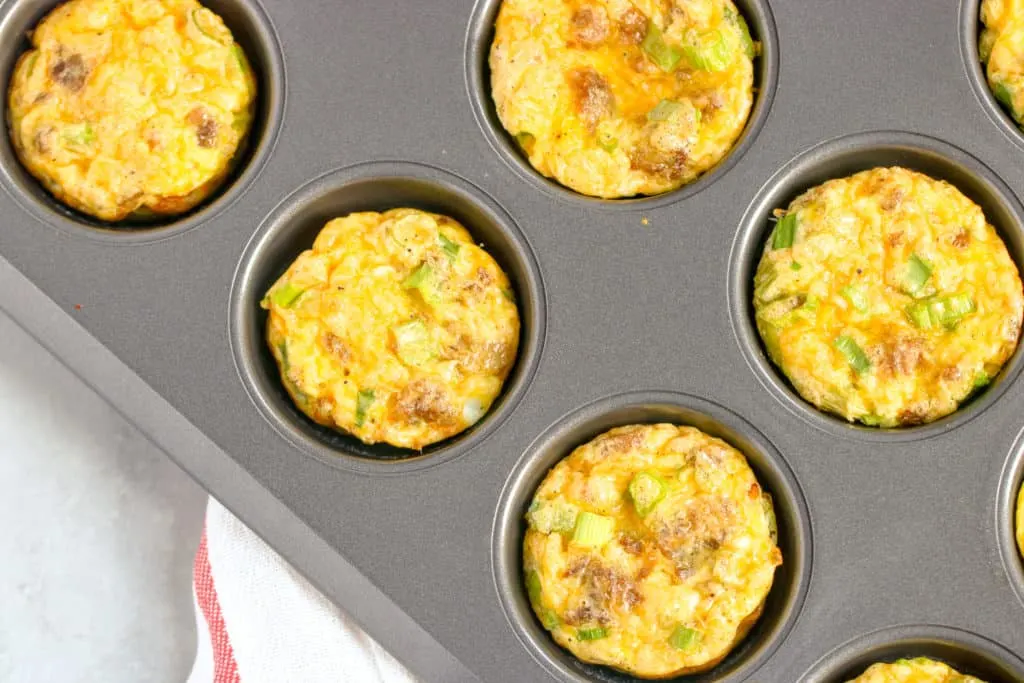 a horizontal image with a corner shot of the sausage egg muffins in the tin