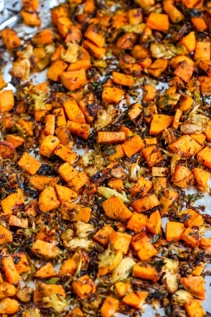 a close up of roasted shaved brussels sprouts and sweet potatoes on aluminum foil