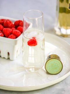 a stemless champagne flute with the st. germain cocktail and a raspberry