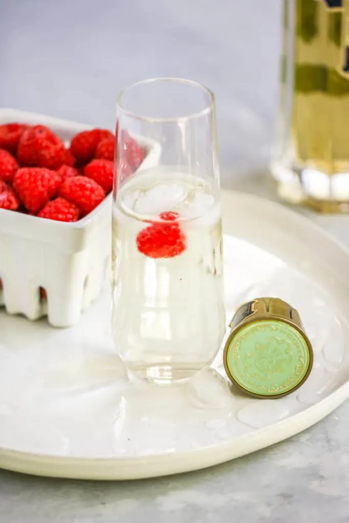 a stemless champagne flute with the st. germain cocktail and a raspberry