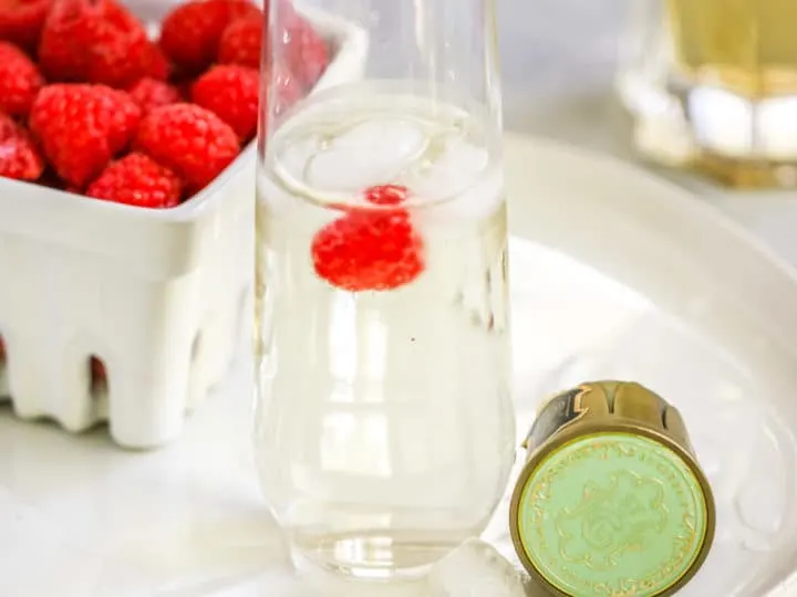 a stemless champagne flute with the st. germain cocktail and a raspberry