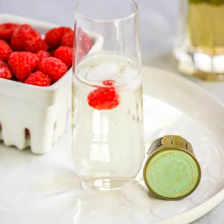 a stemless champagne flute with the st. germain cocktail and a raspberry