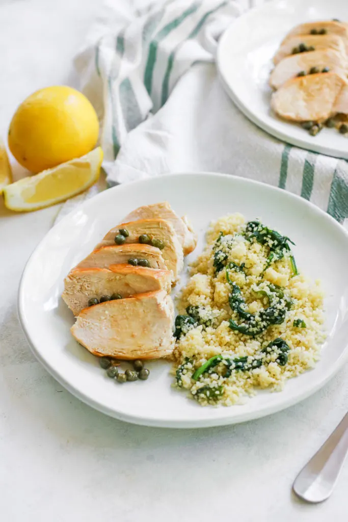 an angle image looking at the white plate of lemon caper chicken