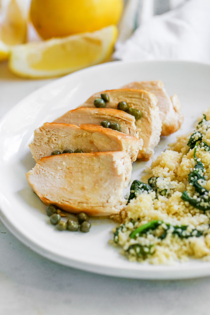 close up shot of Lemon Caper Chicken with lemons in the background