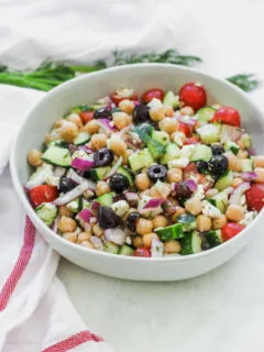 a bowl of Mediterranean Chickpea Salad next to a white napkin with a red stripe