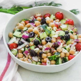 a bowl of Mediterranean Chickpea Salad next to a white napkin with a red stripe