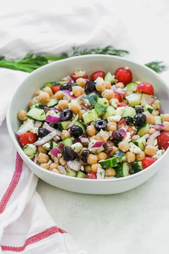 a bowl of Mediterranean Chickpea Salad next to a white napkin with a red stripe