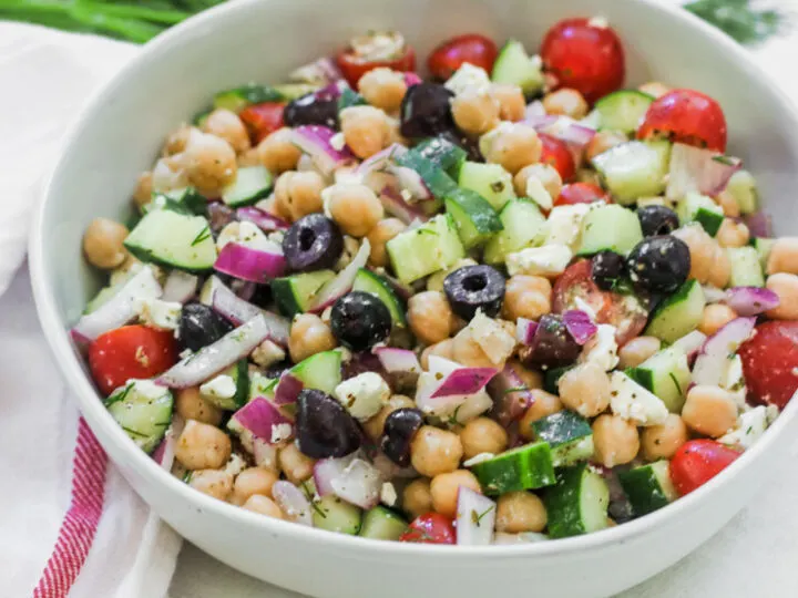 a bowl of Mediterranean Chickpea Salad next to a white napkin with a red stripe