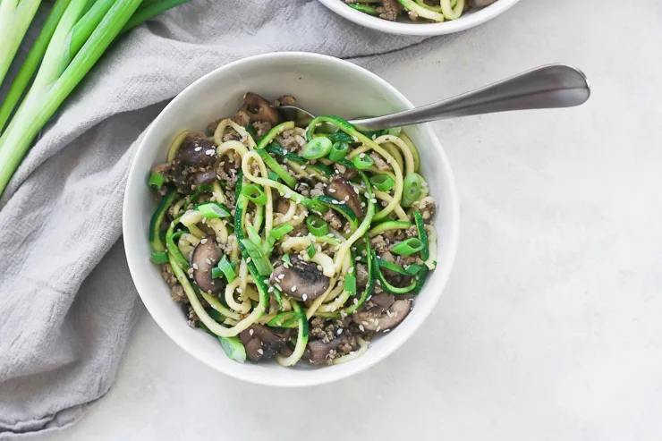 an over head shot of a bowl with sesame zoodles and a fork