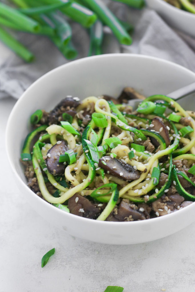 a close up shot showing green onions and sesame seeds on the dish