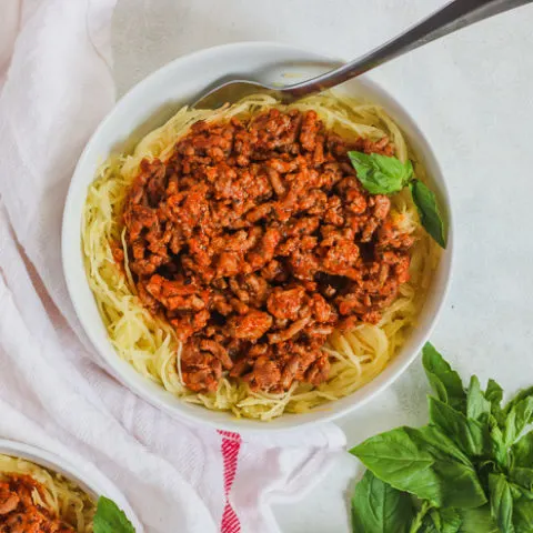 overhead shot of a white bowl with spaghetti squash and meat sauce