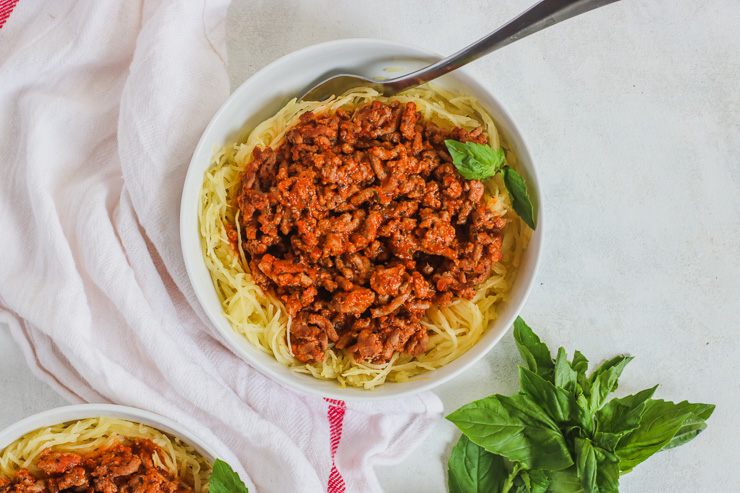 overhead shot of a white bowl with spaghetti squash and meat sauce