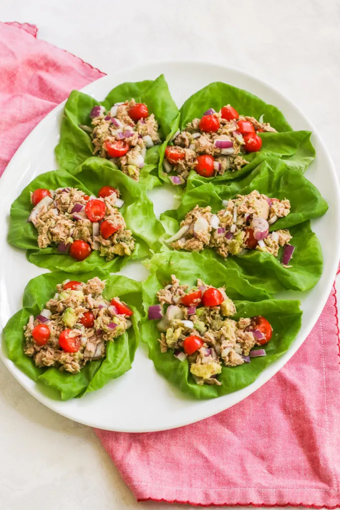 a platter of six tuna avocado lettuce wraps with a red napkin