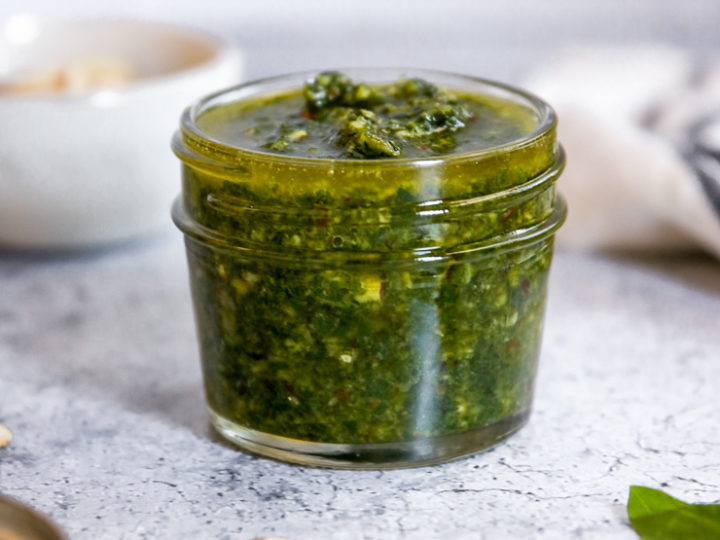 almond pesto in a jar surrounded by some ingredients