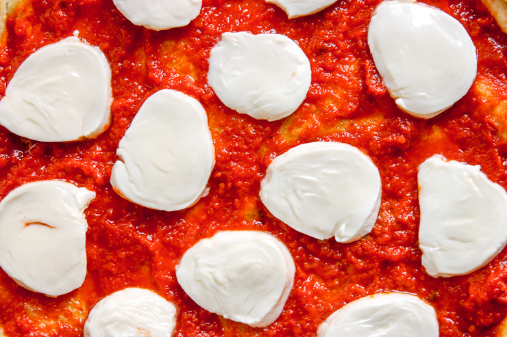 a close up of sliced mozzarella on vodka sauce