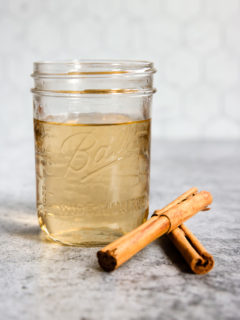 a mason jar of cinnamon simple syrup and cinnamon sticks