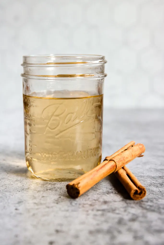 a mason jar of cinnamon simple syrup and cinnamon sticks