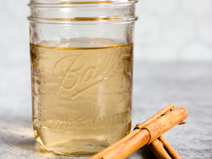 a mason jar of cinnamon simple syrup and cinnamon sticks