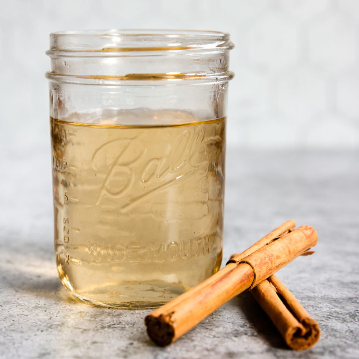 a mason jar of cinnamon simple syrup and cinnamon sticks