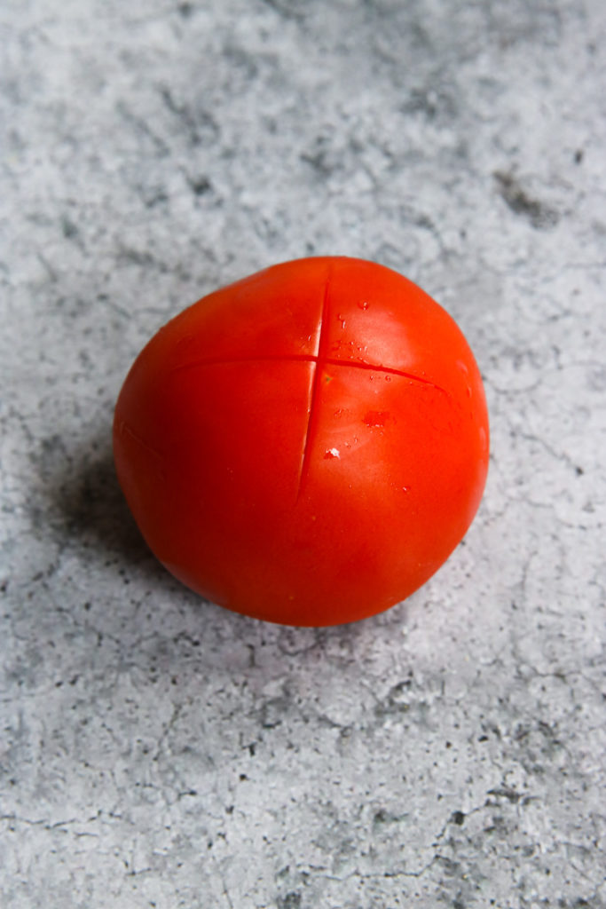 a tomato with an 'x' scored on the bottom