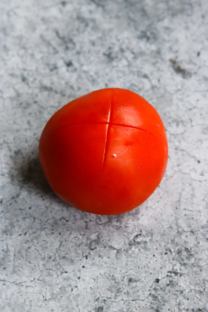 a tomato with an 'x' scored on the bottom