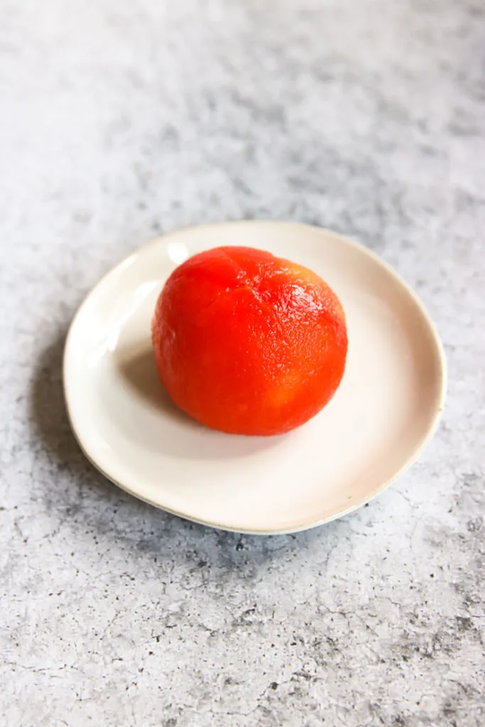 a peeled tomato on a small, white plate