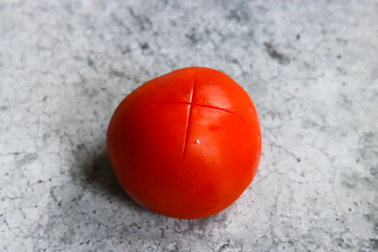 a tomato with an 'x' scored on the bottom