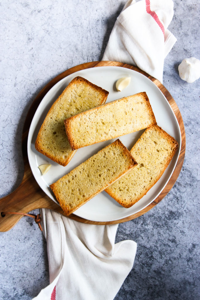 sliced ciabatta bread on a plate with garlic cloves