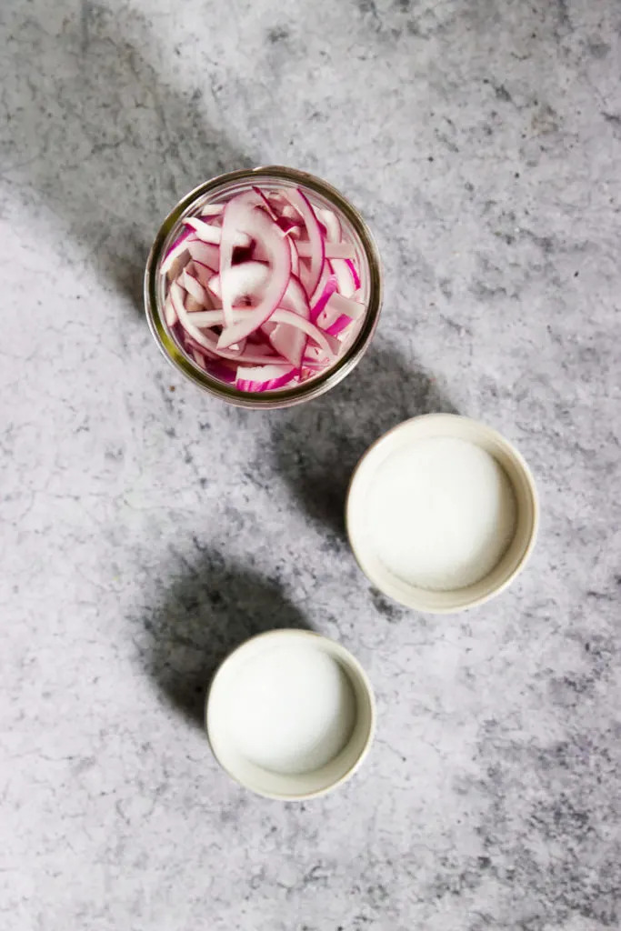 three bowls of ingredients with salt, sugar, and raw red onions