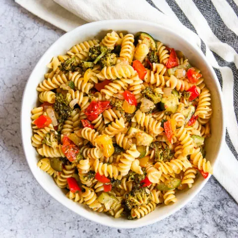 an overhead shot of a white bowl of roasted vegetable pasta