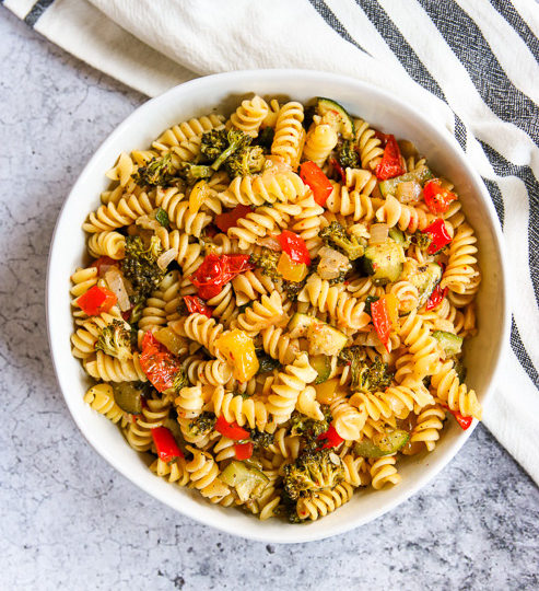 an overhead shot of a white bowl of roasted vegetable pasta