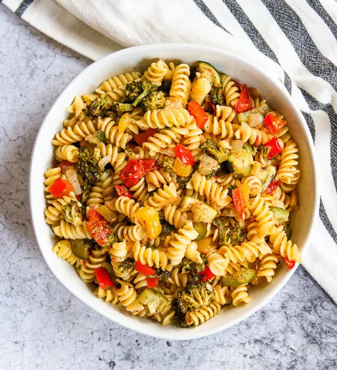 an overhead shot of a white bowl of roasted vegetable pasta