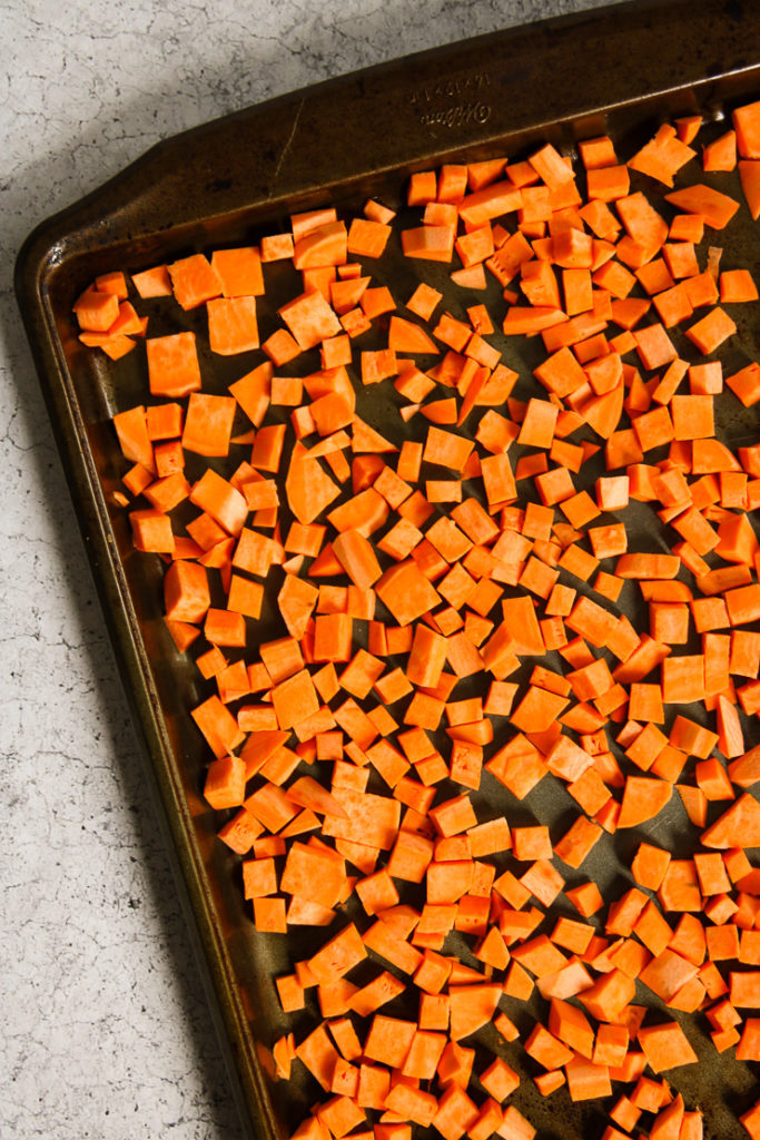 An overhead shot of chopped sweet potatoes on a baking sheet