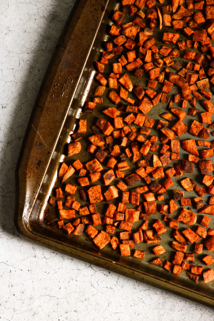 An overhead shot of chopped crispy roasted sweet potatoes on a baking sheet