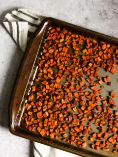 An overhead shot of chopped crispy roasted sweet potatoes on a baking dish