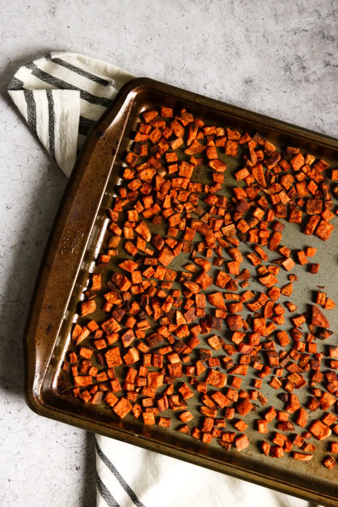 An overhead shot of chopped crispy roasted sweet potatoes on a baking dish