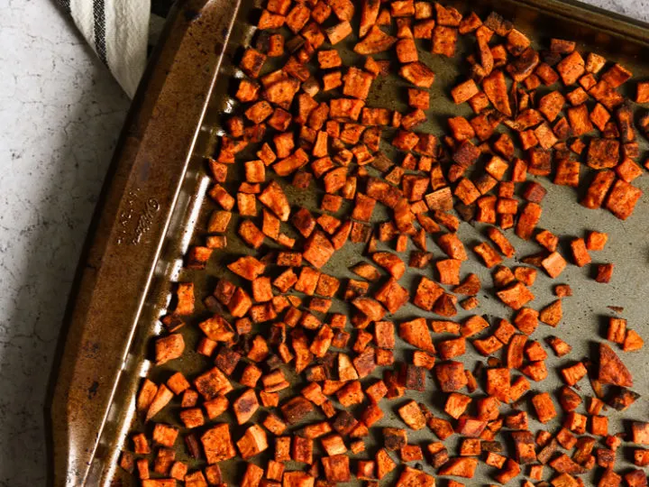 An overhead shot of chopped crispy roasted sweet potatoes on a baking dish