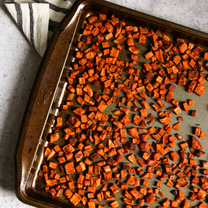 An overhead shot of chopped crispy roasted sweet potatoes on a baking dish