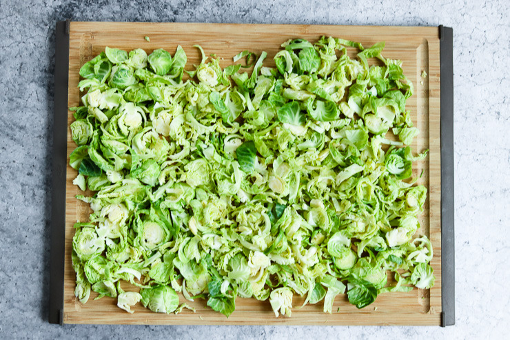 thinly sliced brussels sprouts spread out on a cutting board