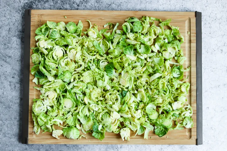 thinly sliced brussels sprouts spread out on a cutting board