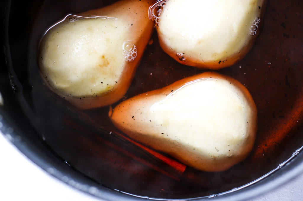 pears in a sauce pot of rose wine and a cinnamon sticks