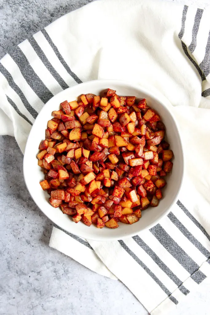 An overhead shot of a white bowl filled with Skillet Breakfast Potatoes