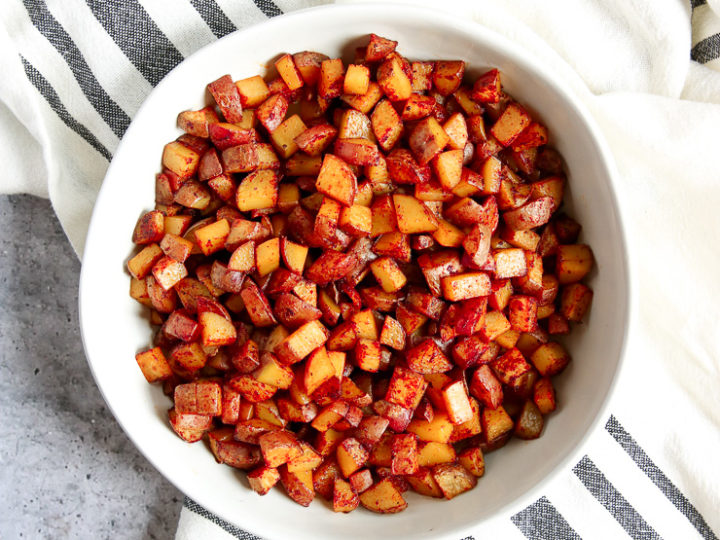 An overhead shot of a white bowl filled with Skillet Breakfast Potatoes