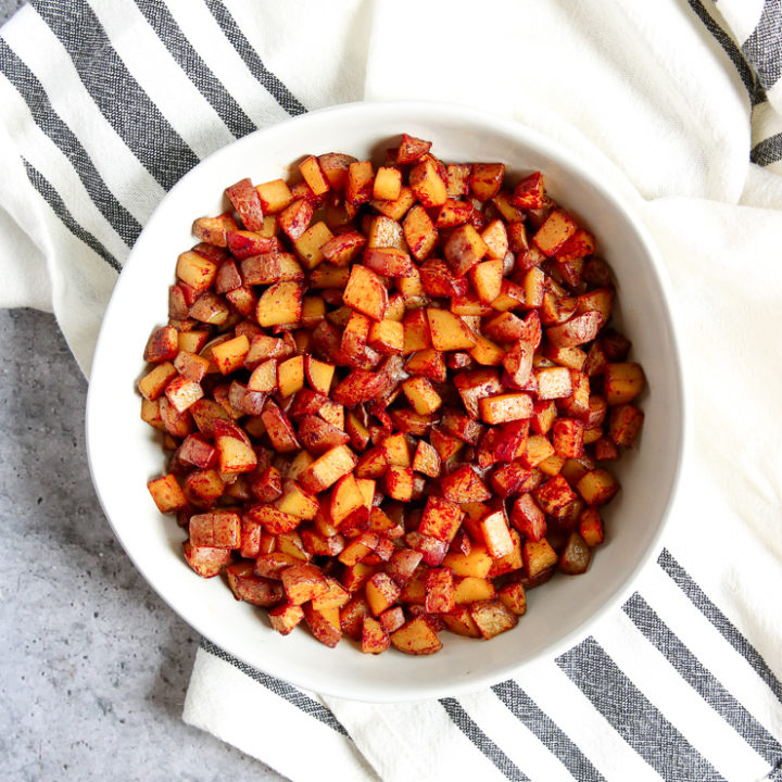 An overhead shot of a white bowl filled with Skillet Breakfast Potatoes