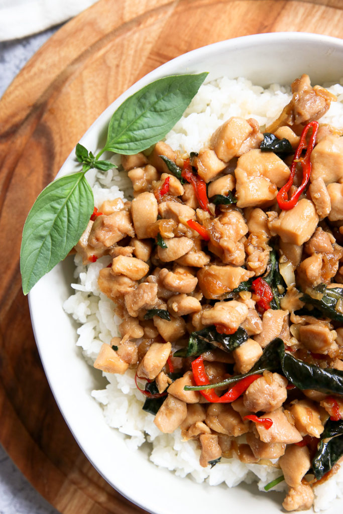 a close up shot of thai basil chicken with thai basil and sliced red chilies