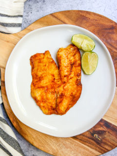 an overhead shot of chili lime tilapia on a white plate on a serving platter